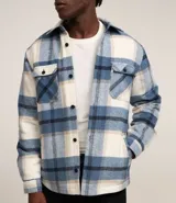 Campera trucker masculina de terciopelo a cuadros en tonos azul, blanco y beige. Tiene cuello inglés, cierre abotonado, bolsillos delanteros y laterales.