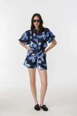 Short de tiro alto con estampado floral en tonos azules y blancos. Presenta pretina estructurada, pliegues frontales, bolsillos laterales y cierre frontal con ganchito interno metálico.