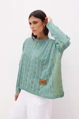 Sweater celeste de punto con diseño de trenzas verticales en color lila. Corte crop y etiqueta de cuero en el frente.