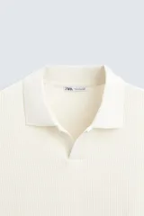 Polo azul marino de punto con textura acanalada vertical, corte regular fit, cuello solapa con abertura frontal y mangas cortas.