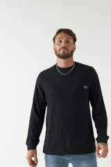 Remera color marrón de manga larga, con bolsillo en el pecho y logo de la marca en etiqueta sobre el bolsillo.