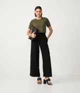 Blusa blanca de poliéster con cuello redondo, mangas cortas, cierre trasero en forma de gota, pequeñas aberturas laterales y acabados en pespuntes en las mangas y el cuello.