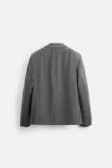 Blazer gris con raya diplomática, corte boxy, cuello con solapas de muesca, manga larga con puño abotonado, bolsillo de vivo en pecho, aberturas en espalda y cierre frontal con dos botones.