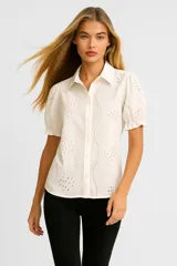 Camisa blanca de algodón con bordado calado, corte holgado, cuello camisero y mangas cortas abullonadas. Cierre frontal con botones.