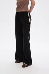 Pantalón negro ancho de viscosa con vivos laterales en blanco, dorado y marrón.