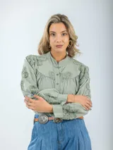 Camisa color crema de broderie, corte holgado, con cuello mao y mangas largas abullonadas con bordados florales.