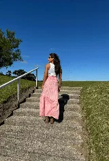 Pollera larga de lino a rayas verticales color rosa y blanco, con cintura elastizada y volado en el ruedo.