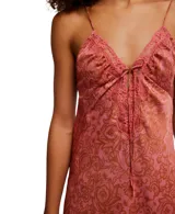 Vestido lencero (slipdress) de largo midi, con estampado paisley en tonos rosados y marrones. Presenta escote pronunciado en V con detalle de encaje en el borde y un lazo central, tirantes finos y una abertura lateral en la falda.