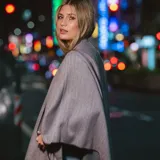 Poncho de acrílico color gris con flecos en el borde inferior.