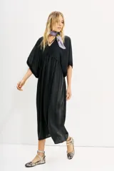 Vestido midi negro de calce amplio y mangas al codo. Tiene apliques de gasa en escote y mangas, y recortes con frunce en la cintura.