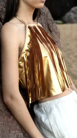 Top corto dorado con flecos marrones, escote halter y espalda descubierta.