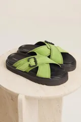 Sandalias planas color beige con tiras cruzadas y hebilla decorativa.