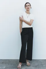 Pantalón color beige de corte ancho, con tiro medio, trabillas en la cintura y raya planchada.
