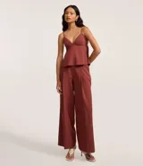 Pantalón de sastrería color terracota, modelo wide leg, con cintura con trabillas y detalle de hebilla lateral. Presenta cierre tradicional y bolsillos tipo cuchillo.