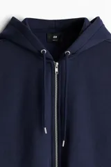 Campera con capucha azul marino, con cierre frontal, bolsillos laterales y puños y cintura acanalados.