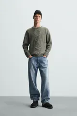 Sweater verde oliva de punto con cuello redondo, manga larga y diseño de trenzas en el frente.