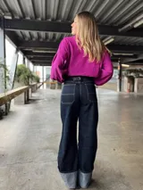 Pantalón de jean azul oscuro de corte recto y tiro alto, con ruedo desflecado y detalle de dobladillo en color gris.