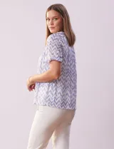 Blusa de microtul estampada con diseño zigzag en tonos celeste y blanco, de la marca Cable & Gauge. Tiene cuello a la base con escote en V y lazo de ajuste, mangas cortas con puño elastizado y forro interno a tono.