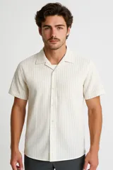 Camisa de manga corta con cuello clásico y cierre de botones frontal. Diseño a rayas verticales en tonos beige y blanco.
