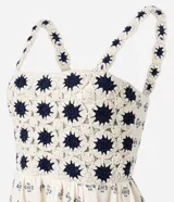Vestido midi de algodón, color crema, con breteles finos. El corpiño presenta un diseño de crochet con motivos florales en azul marino, y la falda evasé tiene un estampado de pequeños íconos abstractos en azul.