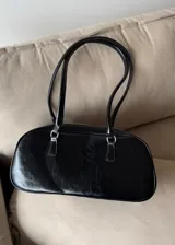 Cartera tipo baguette de cuero sintético color negro con doble asa corta y cierre superior con cremallera.