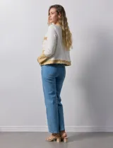 Chaqueta Nanette en tejido tweed color crudo con detalles en denim azul. Tiene cuello a la base, abertura central, bolsillos delanteros, puños con aplique de botones perlados, terminación desflecada y forro interno.