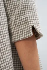 Vestido largo debajo de la rodilla, acampanado, color marrón, con cuello bote, bolsillos laterales y mangas 3/4 con detalle de tajo.