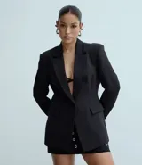 Blazer femenino estructurado de poliéster color negro, con modelo alargado, cuello solapa, cierre frontal con un único botón y bolsillos delanteros.