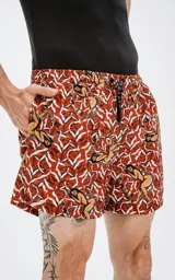 Short de baño color ladrillo con estampado de figuras humanas y corazones blancos.