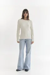 Sweater entallado color crema con textura tejida en relieve.