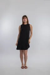Vestido corto negro sin mangas, de corte recto y estilo minimalista.