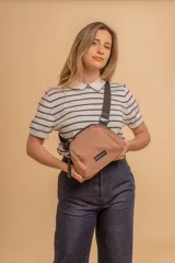 Bandolera pequeña de tela negra, con correa ancha ajustable y cierre superior.