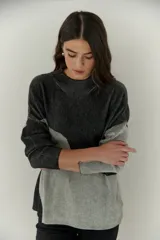 Buzo de punto con diseño geométrico en bloques de color gris y negro, de cuello redondo y mangas largas.