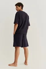 Conjunto de pijama corto de dos piezas. Remera negra de punto de algodón liviano con cuello redondo ribeteado acanalado, hombros caídos y bajo recto. Short negro en popelina de algodón con elástico revestido en la cintura, cierre de botón, bolsillos laterales y un bolsillo parche atrás.