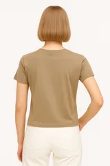 Remera negra de manga corta con estampado frontal que incluye la palabra "Believe" en letras doradas con efecto foil y un diseño abstracto con patrones de cebra y piel de animal.