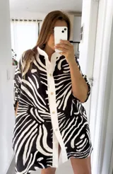 Camisola tipo camisa con estampado de cebra en blanco y negro, con cuello mao y abotonadura frontal blanca.