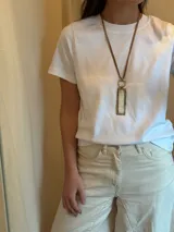 Collar largo con cordón azul, dije rectangular con marco dorado y centro de piedra veteada blanca y gris, y aro dorado.