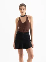 Minifalda de denim negro con cinco bolsillos tradicionales y un volado en el ruedo.