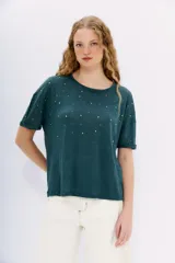 Remera blanca de lino con tachas plateadas en el frente, cuello redondo y mangas cortas.