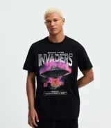 Remera regular de algodón color negro con estampado frontal de un ovni y la frase "Space Cats Invaders" en tonos rosados y morados.