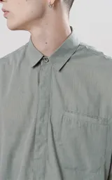 Camisa manga larga color verde militar, de calce oversize, con bolsillo ojal en delantero y cartera escondida.