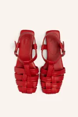 Sandalias franciscanas rojas de cuero con tiras entretejidas y hebilla lateral.