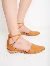 Zapato de cuero color caramelo, con punta fina y tiras cruzadas con hebilla que estilizan el pie y aseguran un calce firme. Su pequeño taco bajo brinda altura justa para el día a día, sin renunciar al confort.