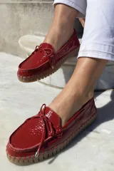 Mocasín náutico dorado de cuero con detalle de lazo en la parte delantera y suela de goma color caramelo.