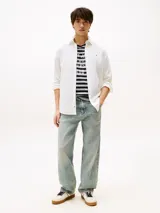 Camisa blanca de manga larga, confeccionada en mezcla de algodón y lino. Tiene corte regular, cuello abotonado, cierre con botones y logo de Tommy Jeans bordado en el pecho.