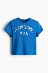 Remera azul con estampado de texto en blanco que dice "New York U.S.A.", de corte clásico y mangas cortas.
