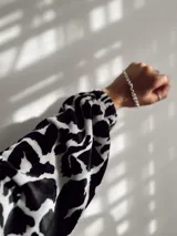 Sobrecamisa de plush con estampado animal print en blanco y negro, con cuello camisero, cierre frontal con botones, mangas largas abullonadas y bolsillos laterales.