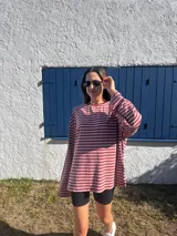 Remera de manga larga con diseño holgado, confeccionada en tejido de punto a rayas horizontales en tonos rosado y marrón.