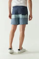 Short de baño con cintura elástica y cordón ajustable, con dos bolsillos laterales y uno trasero. Diseño a rayas horizontales en tonos de azul.