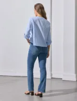 Blusa de algodón a rayas verticales finas en tonos blanco y lila, con escote en V, abertura frontal con botones y mangas largas regulables con presilla y botón. El ruedo termina anudado al frente.